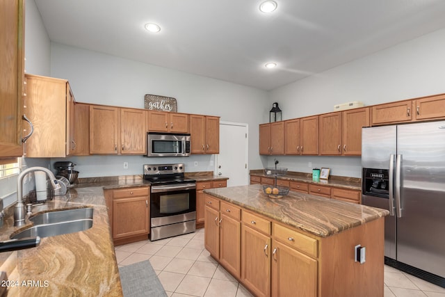 kitchen with appliances with stainless steel finishes, sink, light stone counters, and a center island