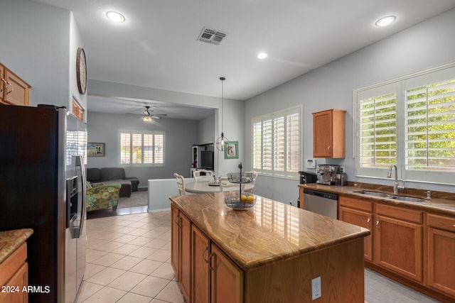 kitchen with appliances with stainless steel finishes, decorative light fixtures, sink, ceiling fan, and a center island