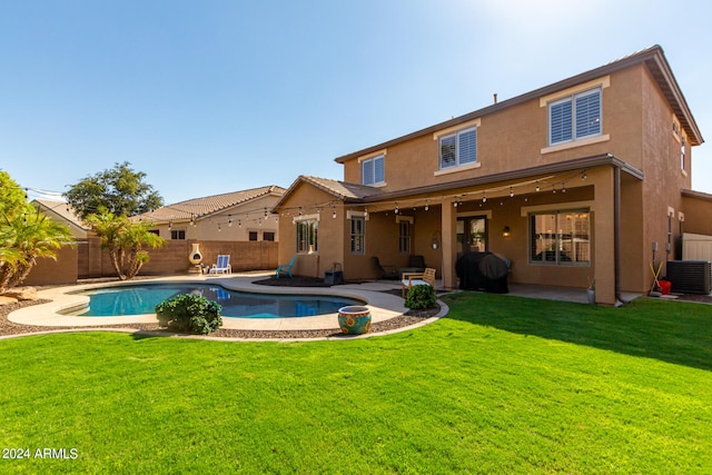 rear view of property featuring central air condition unit, a fenced in pool, a yard, and a patio area