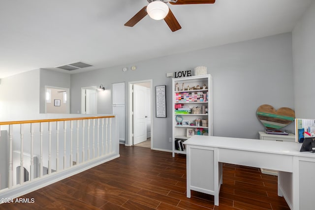 unfurnished office featuring dark wood-type flooring, ceiling fan, and built in desk