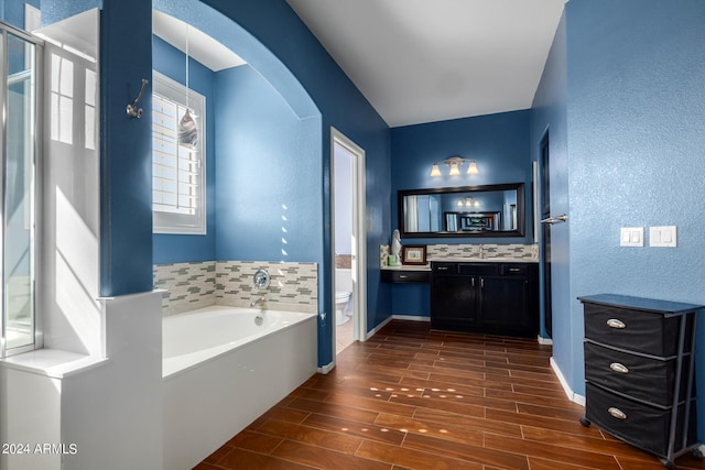 bathroom with hardwood / wood-style floors, vanity, toilet, and a bathing tub