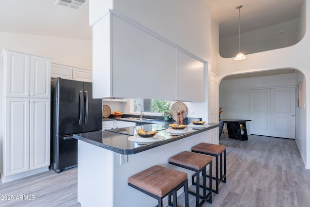 kitchen with visible vents, arched walkways, a sink, freestanding refrigerator, and a high ceiling
