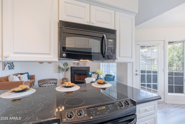 kitchen featuring black microwave, white cabinetry, and electric stove