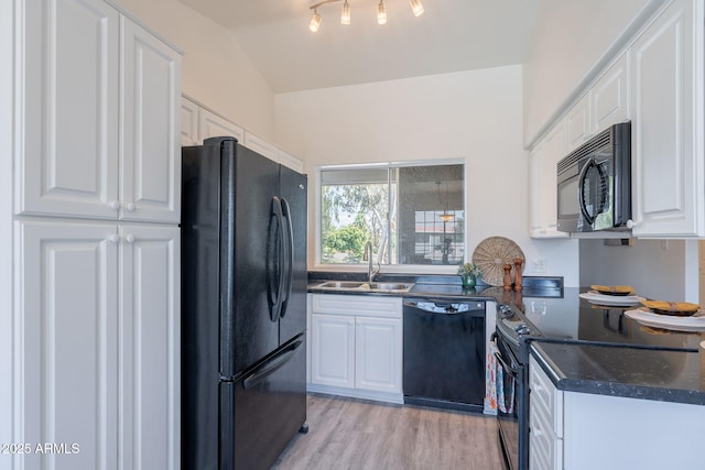 kitchen featuring a sink, white cabinetry, black appliances, and vaulted ceiling