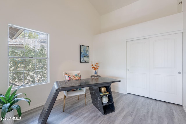 office area featuring baseboards, wood finished floors, and high vaulted ceiling