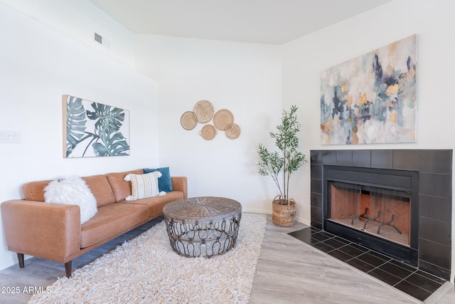 living area featuring visible vents, baseboards, wood finished floors, and a fireplace