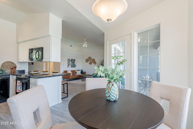 dining space with ceiling fan, light wood finished floors, and lofted ceiling