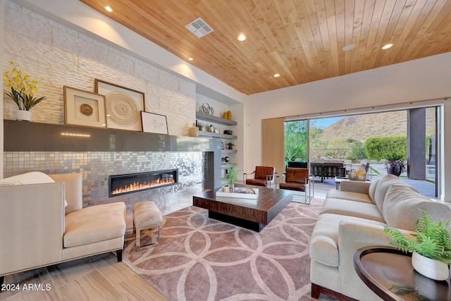 living room featuring built in shelves, light wood-type flooring, wood ceiling, and a tiled fireplace