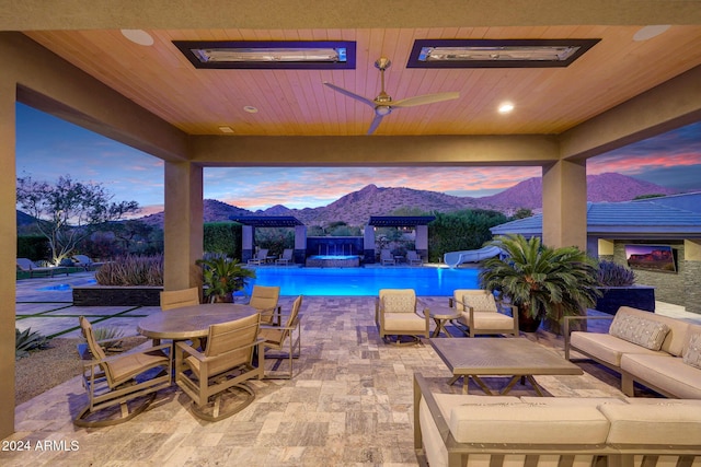 patio terrace at dusk featuring a mountain view, outdoor lounge area, and ceiling fan