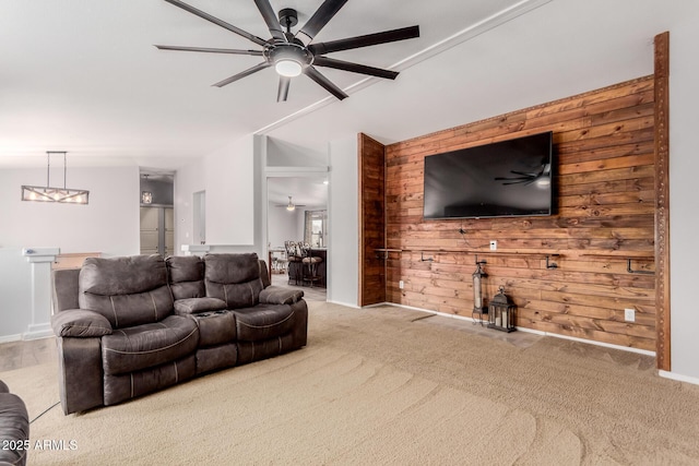 carpeted living room with baseboards, wooden walls, and a ceiling fan