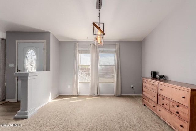 interior space featuring light carpet, a healthy amount of sunlight, and baseboards