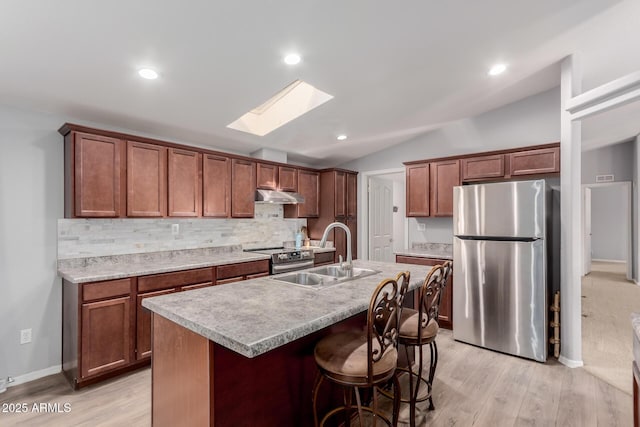 kitchen featuring under cabinet range hood, stainless steel appliances, tasteful backsplash, and a sink