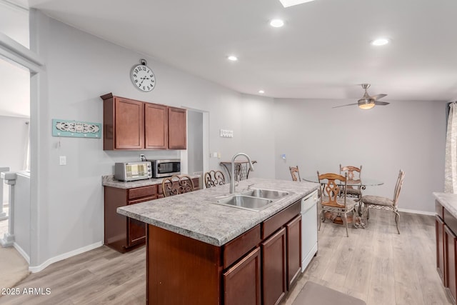 kitchen featuring dishwasher, stainless steel microwave, light wood-style flooring, and a sink