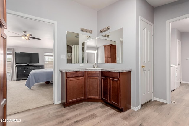 ensuite bathroom featuring ceiling fan, separate washer and dryer, wood finished floors, and vanity