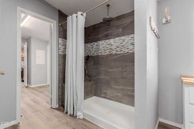 full bath featuring baseboards, wood finished floors, and a stall shower