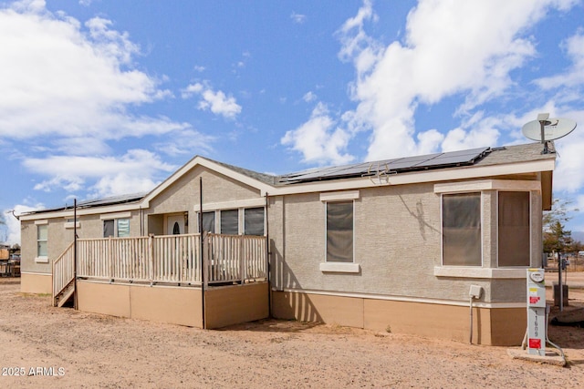 back of house with solar panels and stucco siding