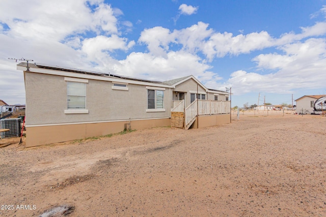 rear view of property featuring solar panels, fence, and central AC