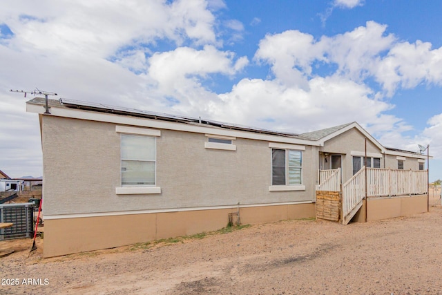 rear view of house featuring central AC and roof mounted solar panels