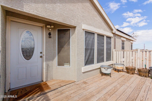 doorway to property with stucco siding and a wooden deck