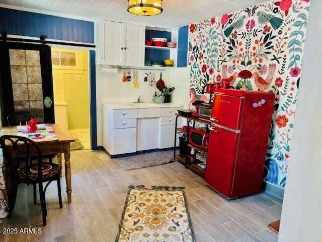 kitchen with a barn door, white cabinets, light countertops, wood tiled floor, and open shelves