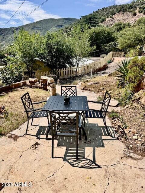 view of patio / terrace featuring fence, a mountain view, and outdoor dining area
