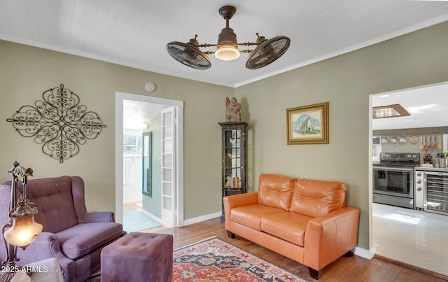 living room with beverage cooler, crown molding, baseboards, and wood finished floors