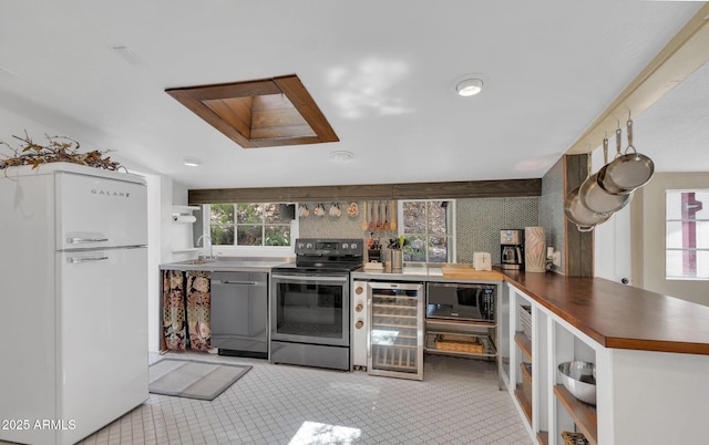 kitchen featuring a peninsula, plenty of natural light, wine cooler, and appliances with stainless steel finishes