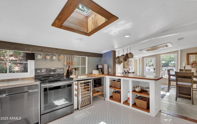 kitchen featuring beverage cooler, visible vents, decorative backsplash, lofted ceiling with skylight, and stainless steel appliances