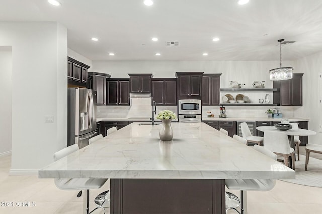 kitchen with decorative light fixtures, stainless steel appliances, a spacious island, and a kitchen bar