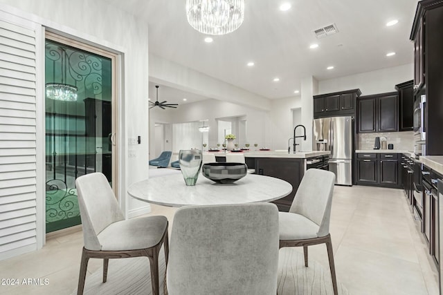 tiled dining space featuring sink and ceiling fan with notable chandelier