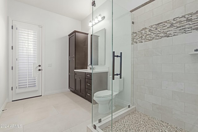 bathroom featuring toilet, vanity, tile patterned floors, and a shower with shower door