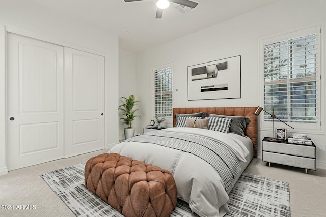 bedroom featuring multiple windows, light carpet, ceiling fan, and a closet