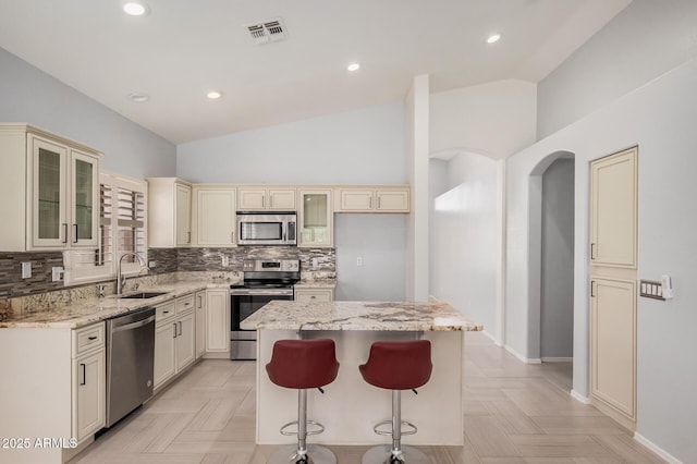 1712 E Saratoga St, Gilbert, AZ 85296 - kitchen featuring lofted ceiling, cream cabinetry, stainless steel appliances, visible vents, and a sink