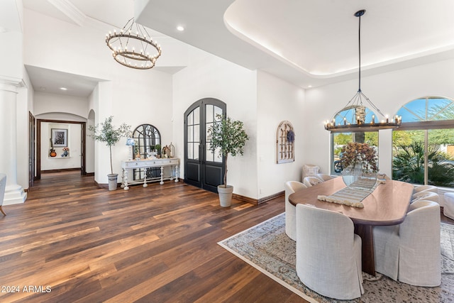 dining space featuring dark hardwood / wood-style flooring, a towering ceiling, ornate columns, and french doors