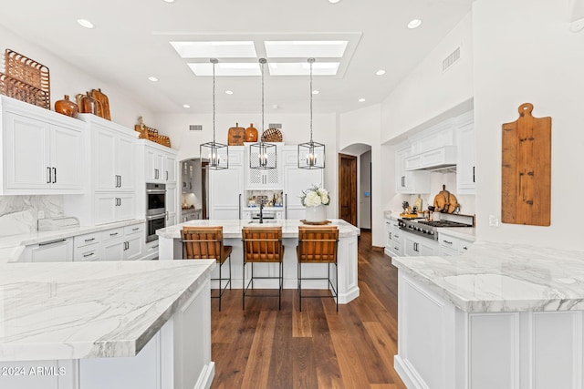 kitchen featuring pendant lighting, a center island with sink, white cabinetry, and appliances with stainless steel finishes