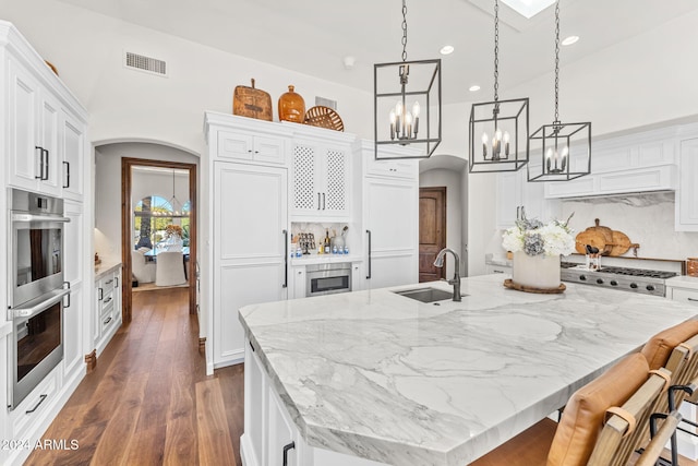 kitchen with backsplash, sink, an island with sink, white cabinetry, and stainless steel appliances