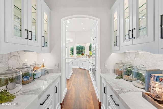 bar with decorative backsplash, dark hardwood / wood-style floors, white cabinetry, and light stone countertops