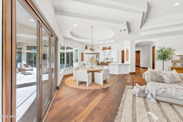 dining area with a tray ceiling, a chandelier, and hardwood / wood-style flooring