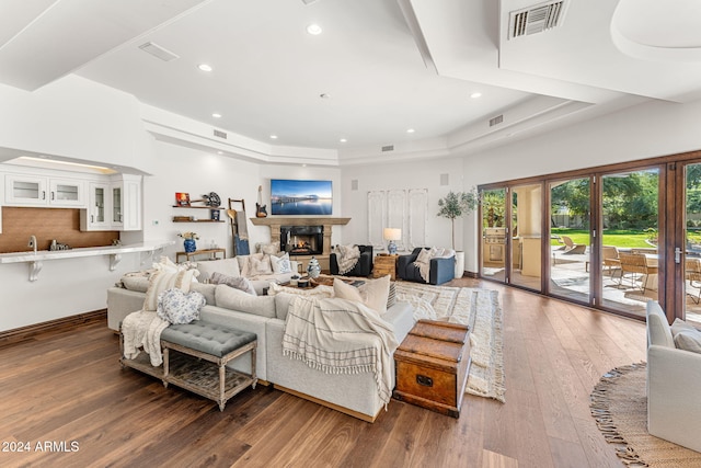 living room with dark wood-type flooring, a tray ceiling, and french doors