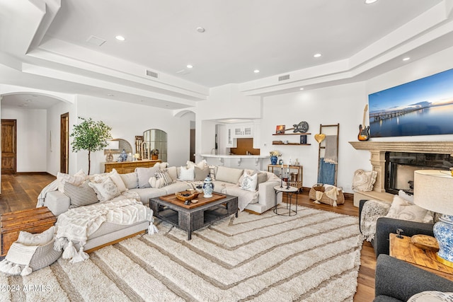 living room with a tray ceiling, a fireplace, and hardwood / wood-style flooring