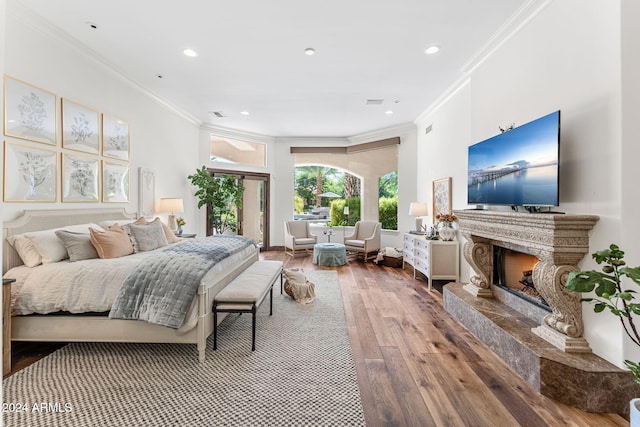 bedroom featuring a high end fireplace, wood-type flooring, and crown molding