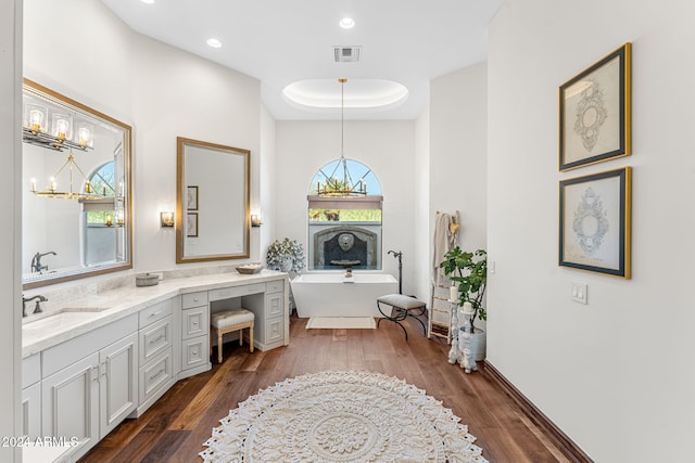 bathroom featuring a chandelier, vanity, hardwood / wood-style flooring, and a bathing tub