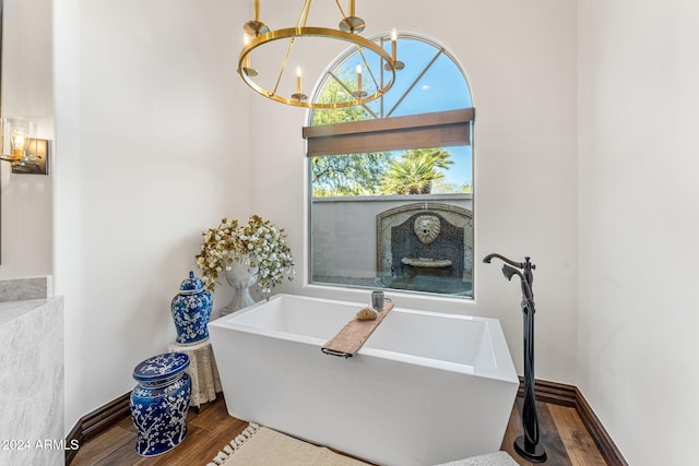 bathroom featuring hardwood / wood-style flooring, a bathing tub, and an inviting chandelier