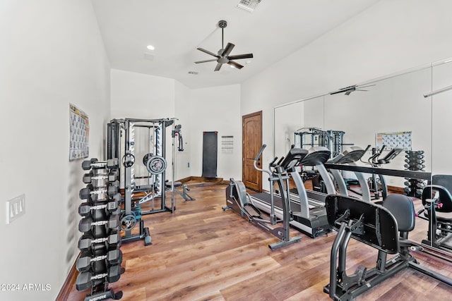 gym with hardwood / wood-style flooring, ceiling fan, and a high ceiling