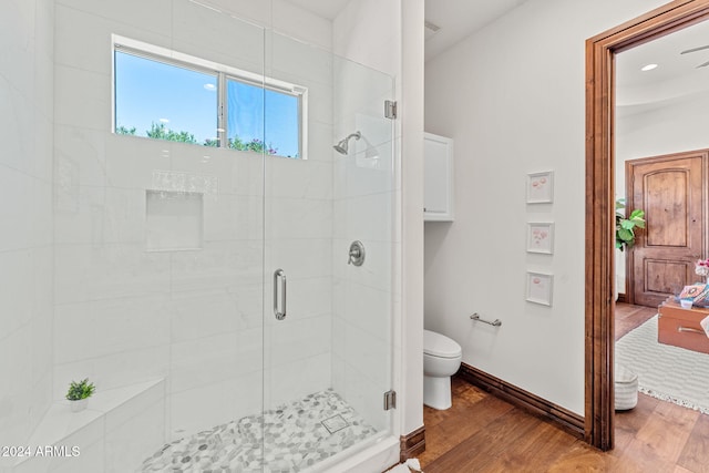 bathroom with hardwood / wood-style flooring, toilet, and an enclosed shower