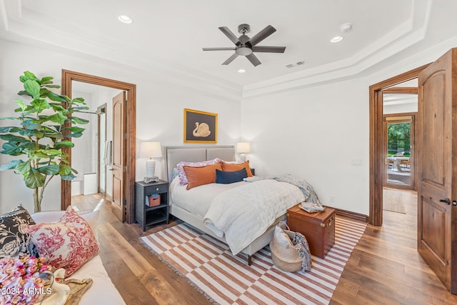 bedroom with ceiling fan, dark wood-type flooring, and a tray ceiling