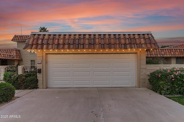 garage at dusk with concrete driveway