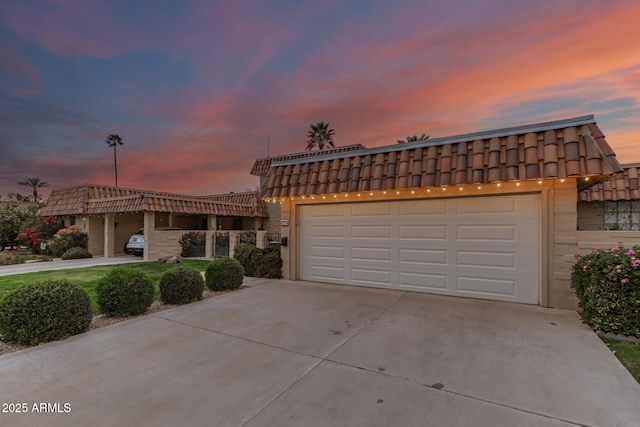 view of front of property featuring a garage, concrete driveway, a tile roof, and mansard roof