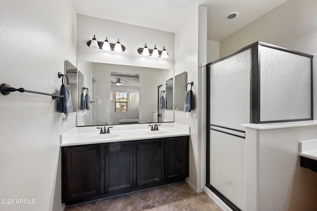 full bath with a stall shower, double vanity, ceiling fan, and a sink