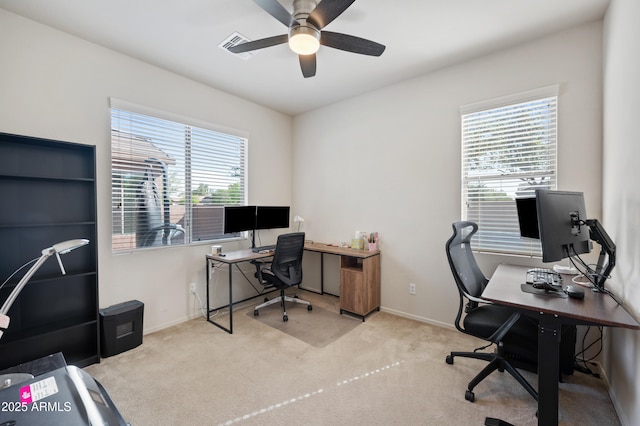 carpeted office space featuring baseboards and a ceiling fan